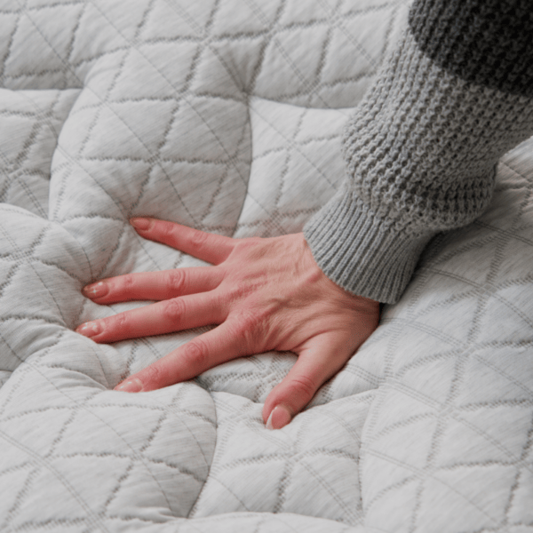 person pressing hand into mattress